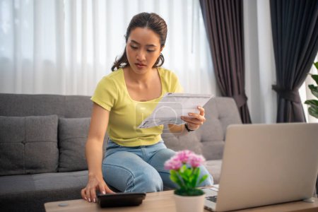Woman using calculator to check total sum of household bills