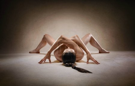 Belle fille de fitness sexy nue avec une grande figure fléchissant son corps parfait dans une pose de yoga au studio. Pose d'araignée.