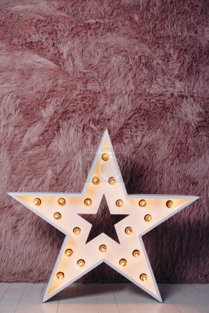 Téléchargez les photos : Big Large decorative retro star with lots of burning lights on pink fur background star with light bulbs near the pink fur wall - en image libre de droit