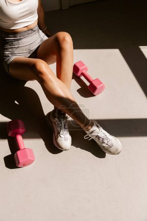 Foto de Imagen de una hermosa mujer caucásica en forma joven haciendo ejercicio con pesas de color rosa en el interior - Imagen libre de derechos