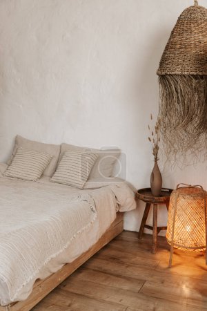 Foto de Blanco simple wabi sabi dormitorio de diseño con lámparas tejidas y cómoda cama con sábanas blancas, foto real - Imagen libre de derechos