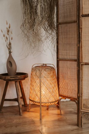 Photo for Stylish wabi sabi bedroom interior design with lighten floor rattan lamp, bedside table and bamboo screen - Royalty Free Image