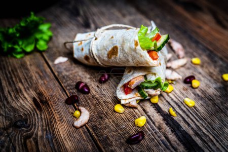 Photo for Traditional mexican tortilla wrap with chicken meat and vegetables on wood table - Royalty Free Image