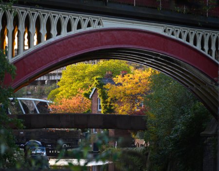 Téléchargez les photos : Un vieux pont sur le canal dans le centre-ville de Manchester, Royaume-Uni avec des arbres d'automne en arrière-plan. - en image libre de droit