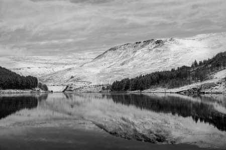Photo for Snow covered Dovestone Reservoir and reflection of a landscape in its water in the Greater Manchester UK - Royalty Free Image