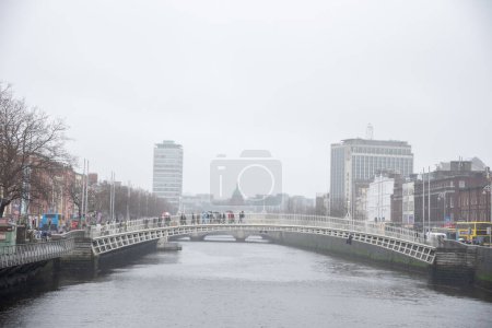 Foto de DUBLÍN, IRLANDA-ABRIT 02,2015-Los peatones cruzan el puente Ha Penny Bridge sobre el río Liffey en Dublín Irlanda - Imagen libre de derechos