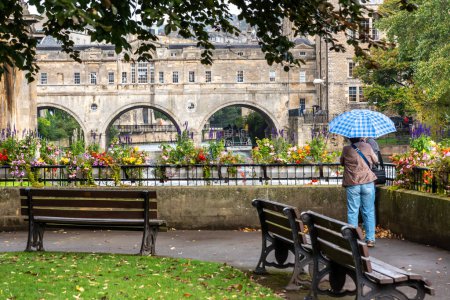 Téléchargez les photos : Des hommes tenant un parapluie face au pont Pulteny à Bath au Royaume-Uni - en image libre de droit