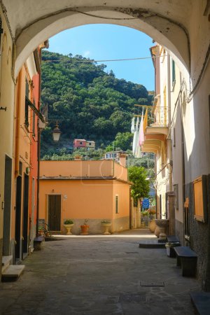 Téléchargez les photos : Rue dans la vieille ville de Framura, Ligurie, Italie à travers l'arche et vue sur les montagnes. - en image libre de droit