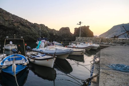 Téléchargez les photos : Bateaux dans le port de Framura, Ligurie, Italie pendant le coucher du soleil ciel à travers les falaises - en image libre de droit