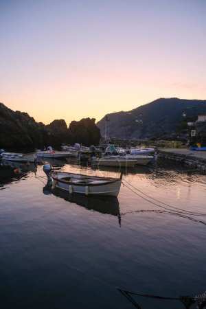 Téléchargez les photos : Bateaux dans le port de Framura, Ligurie, Italie pendant le coucher du soleil ciel à travers les falaises - en image libre de droit