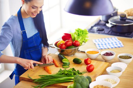 Foto de Mujer joven cortando verduras en la cocina en casa. - Imagen libre de derechos