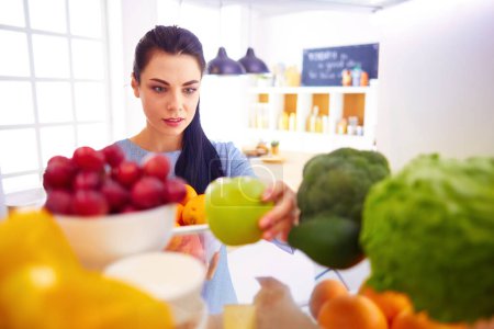 Photo for Smiling woman taking a fresh fruit out of the fridge, healthy food concept. - Royalty Free Image