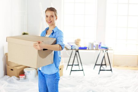 Téléchargez les photos : Jeune femme déménageant dans une nouvelle maison tenant des boîtes en carton
 . - en image libre de droit