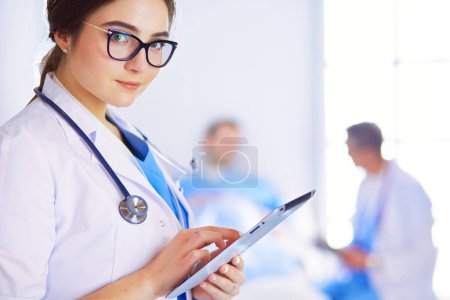 Médico femenino usando tableta en el vestíbulo del hospital,