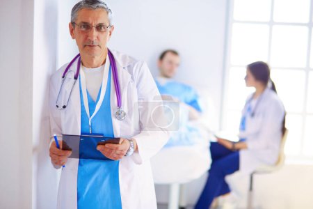 Photo for Doctor holding folder in front of a patient and a doctor. - Royalty Free Image