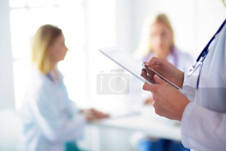 Téléchargez les photos : Portrait d'une jeune femme médecin, aipads à la main, dans un cabinet médical. - en image libre de droit