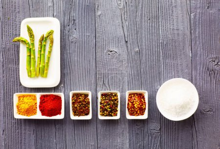 Photo for Various ground spices in bowl on old wooden table with asparagus. - Royalty Free Image