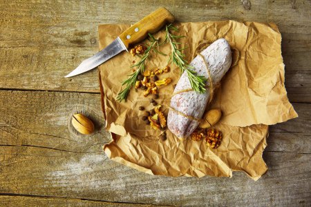 Téléchargez les photos : Salami italien avec sel de mer, romarin, ail et noix sur papier. Style rustique. Vue du dessus. - en image libre de droit