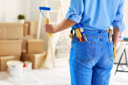 Photo for Pretty woman painting interior wall of home with paint roller. - Royalty Free Image