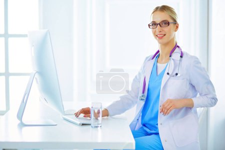 Photo for Portrait of young female doctor sitting at desk in hospital. - Royalty Free Image