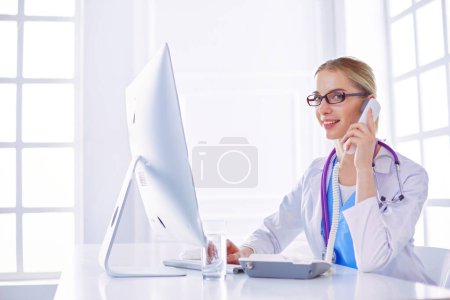 Photo for Female doctor having a phone call on medical office. - Royalty Free Image