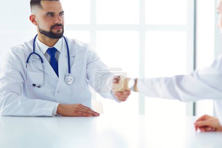 Téléchargez les photos : Docteur serrant la main d'un patient masculin au bureau. - en image libre de droit