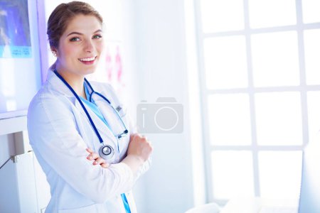 Téléchargez les photos : Jeune femme médecin en uniforme blanc debout dans le bureau des cliniques. - en image libre de droit