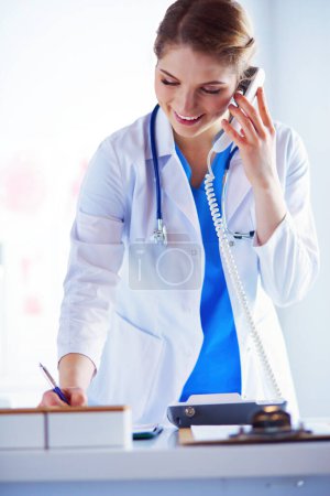 Photo for Serious doctor on the phone in her office. - Royalty Free Image