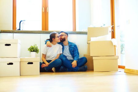 Foto de Feliz joven pareja sentada en el suelo de una casa nueva rodeada de cajas
. - Imagen libre de derechos