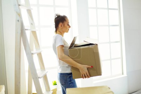 Photo for A beautiful single young woman unpacking boxes and moving into a new home. - Royalty Free Image