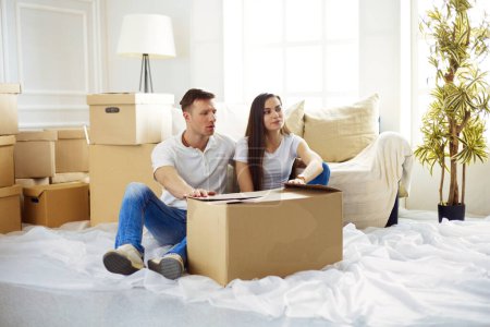 Téléchargez les photos : Joyeux jeune couple déballer des boîtes dans leur nouvelle maison
. - en image libre de droit