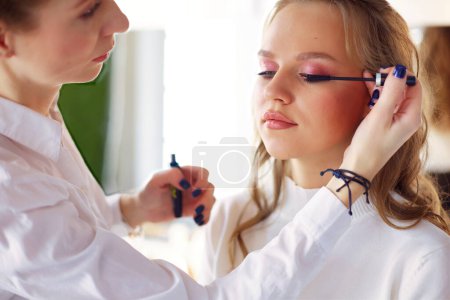 Photo for Make up artist doing professional make up of young woman. - Royalty Free Image