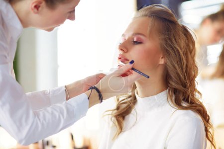 Téléchargez les photos : Maquilleuse faisant du maquillage professionnel de jeune femme. - en image libre de droit