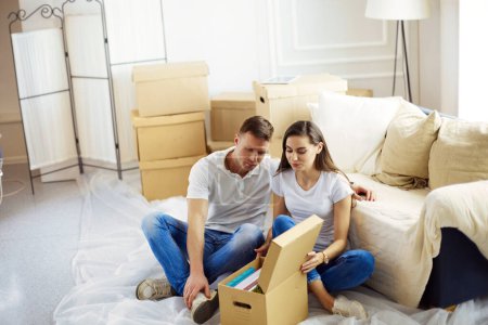 Photo for Happy young couple unpacking or packing boxes and moving into a new home. - Royalty Free Image