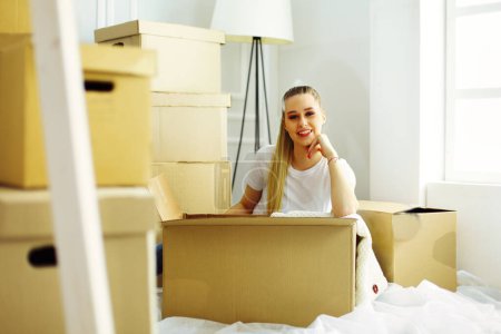 Foto de Una hermosa mujer joven soltera desempacando cajas y mudarse a un nuevo hogar. - Imagen libre de derechos