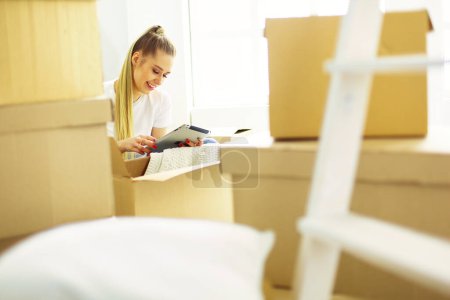Foto de Una hermosa mujer joven soltera desempacando cajas y mudarse a un nuevo hogar. - Imagen libre de derechos