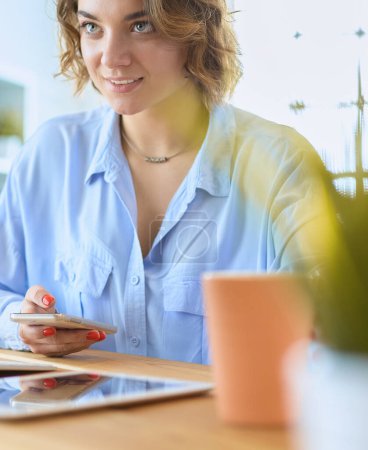 Téléchargez les photos : Femme heureuse travaillant en utilisant plusieurs appareils sur un bureau à la maison. - en image libre de droit