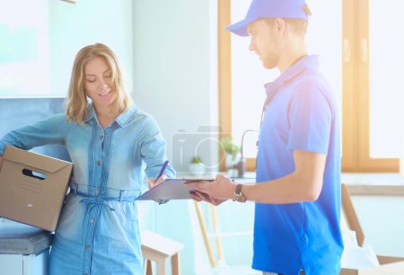 Photo for Smiling delivery man in blue uniform delivering parcel box to recipient - courier service concept. Smiling delivery man in blue uniform. - Royalty Free Image