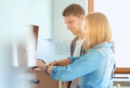 Photo for Young couple carrying big cardboard box at new home.Moving house. Young couple. - Royalty Free Image