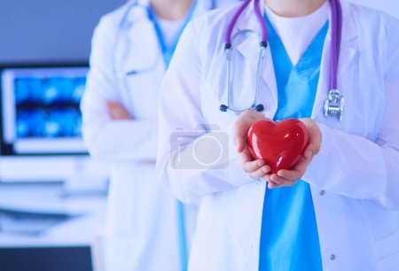 Téléchargez les photos : Pouls recadré de deux jeunes médecins femelle avec stéthoscope tenant le cœur - en image libre de droit