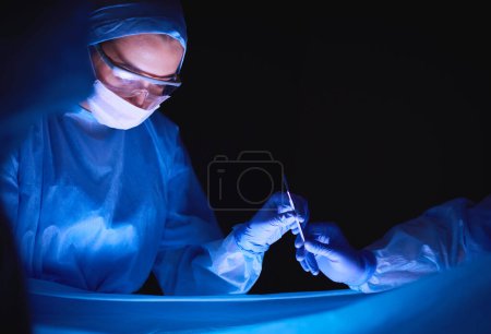 Foto de Equipo de médicos en cirugía en un fondo oscuro - Imagen libre de derechos