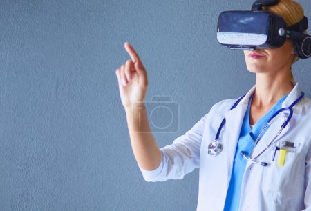 Téléchargez les photos : Médecin féminin portant des lunettes de réalité virtuelle isolées sur fond blanc - en image libre de droit
