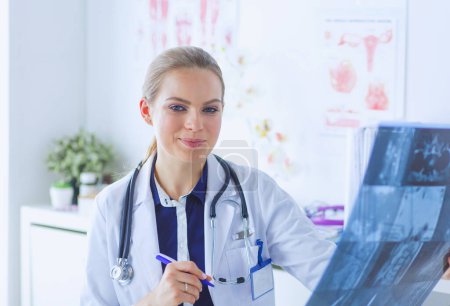 Téléchargez les photos : Jeune médecin attrayant femme regardant l'image de rayons X. - en image libre de droit