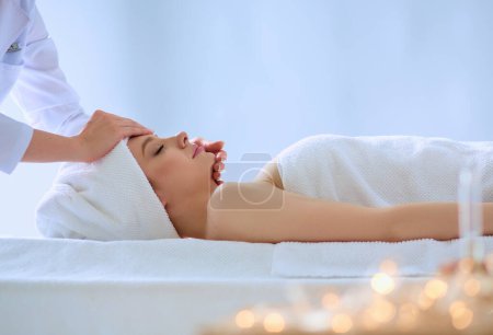 Téléchargez les photos : Jeune femme allongée sur une table de massage, relaxante les yeux fermés. Femme. Salon de spa. - en image libre de droit