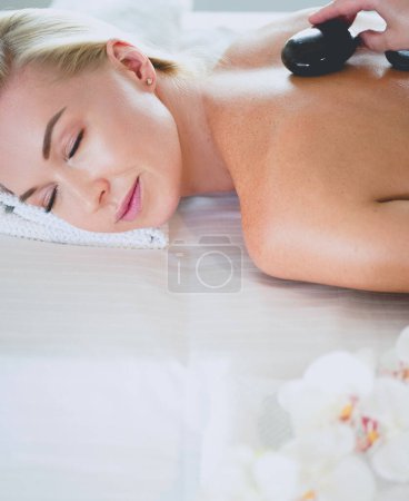 Photo pour Jeune femme dans le salon de spa, se faire masser les pierres. - image libre de droit