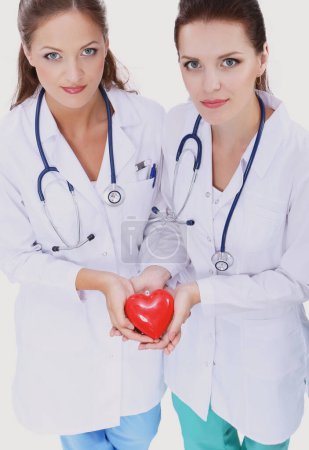 Foto de Dos doctora sosteniendo un corazón rojo
 . - Imagen libre de derechos