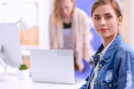 Photo for Two young woman standing near desk with instruments, plan and laptop. - Royalty Free Image