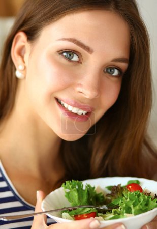 Photo for Young woman eating salad and holding a mixed salad . - Royalty Free Image