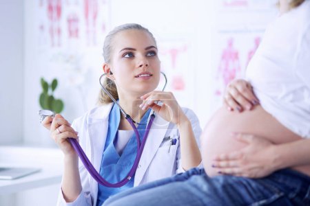 Téléchargez les photos : Jeune femme médecin avec stéthoscope parlant avec une femme enceinte à l'hôpital - en image libre de droit
