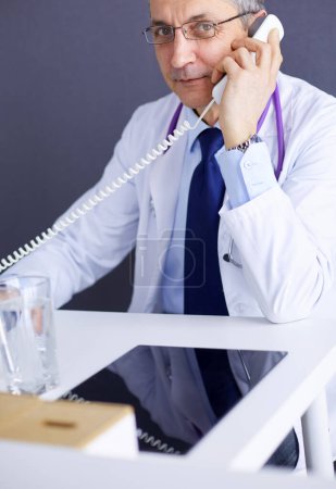Photo for Portrait of senior doctor sitting in medical office. - Royalty Free Image